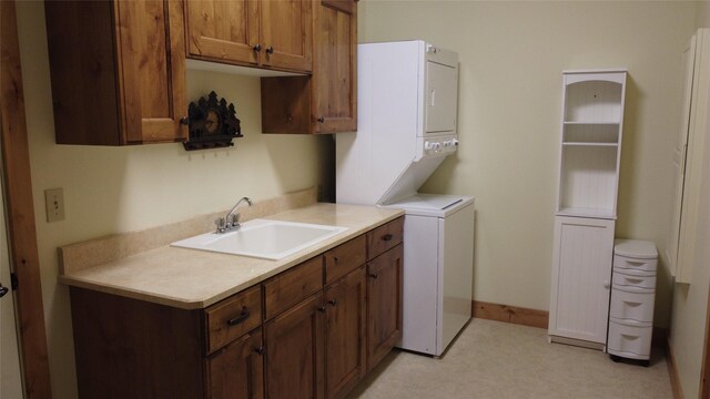 laundry room featuring stacked washer and dryer, sink, and cabinets