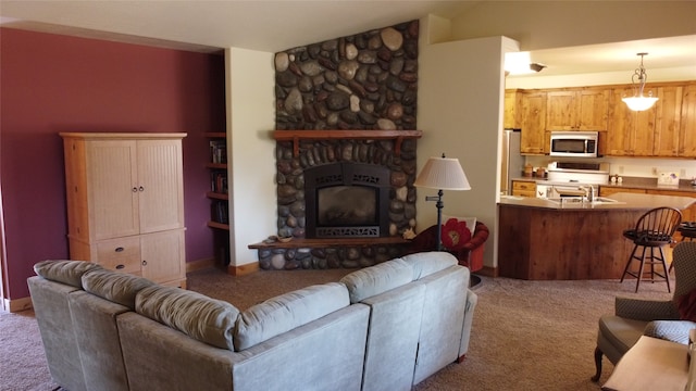 living room featuring a stone fireplace, sink, and light colored carpet