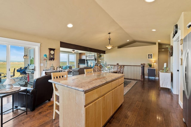 881 Lone Coyote Trl, Kalispell, MT 59901 - kitchen featuring light brown cabinetry, open floor plan, a kitchen bar, a center island, and dark wood-style flooring