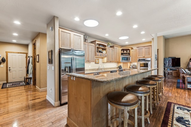 kitchen with a center island, appliances with stainless steel finishes, dark stone counters, and light hardwood / wood-style flooring