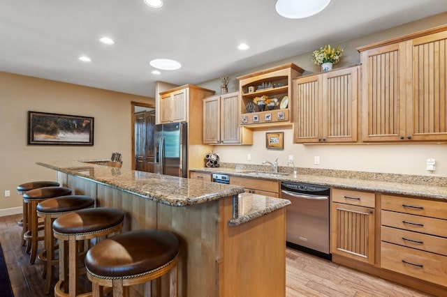 kitchen with stainless steel appliances, light wood-type flooring, a kitchen island, and stone countertops