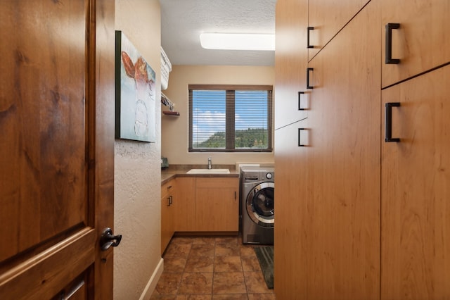 washroom featuring dark tile patterned floors, washer / dryer, sink, and cabinets