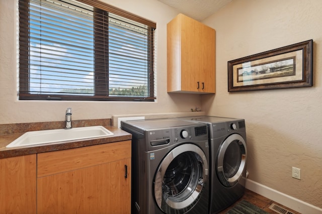 laundry area with cabinets, washing machine and dryer, and sink