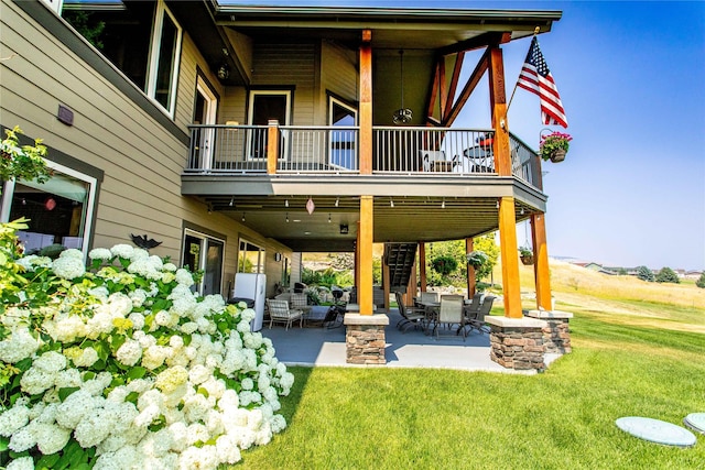 rear view of property featuring a yard, a patio area, and a balcony