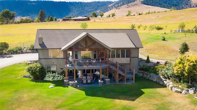 rear view of property with a deck with mountain view, a rural view, stairway, a yard, and a patio
