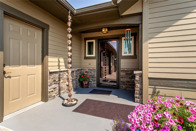 view of exterior entry with stone siding and a porch