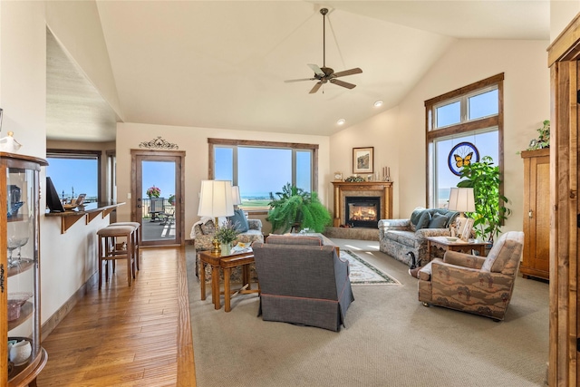 living room featuring ceiling fan, a glass covered fireplace, wood finished floors, and plenty of natural light