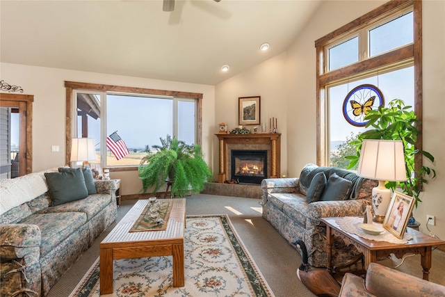 carpeted living room featuring ceiling fan, vaulted ceiling, and a tiled fireplace