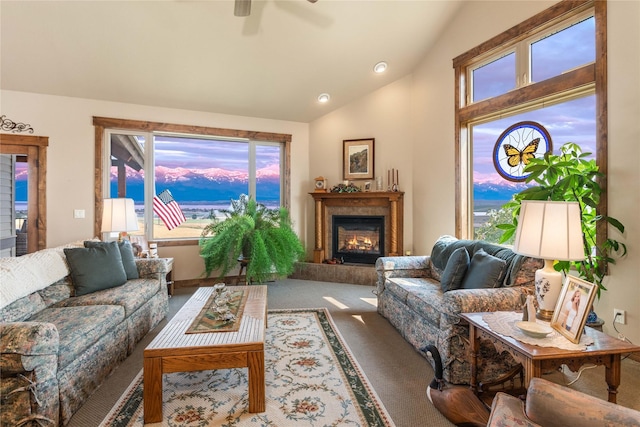 carpeted living area featuring a fireplace, lofted ceiling, and a ceiling fan