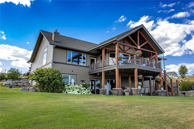 back of house with a wooden deck, a lawn, a shingled roof, and a chimney