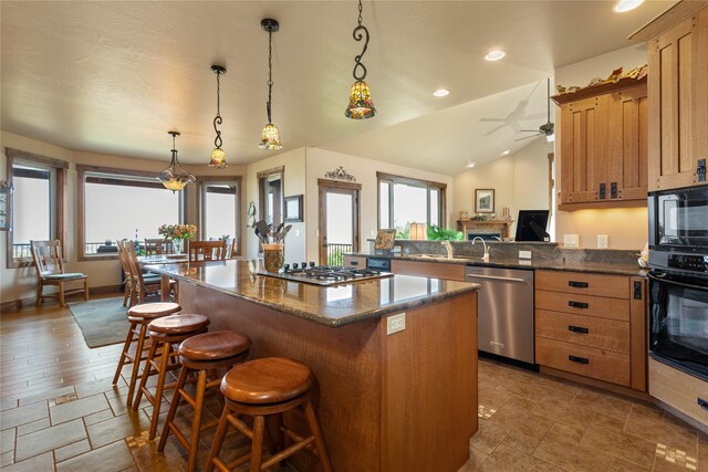 kitchen featuring black appliances, vaulted ceiling, a breakfast bar, pendant lighting, and hardwood / wood-style flooring