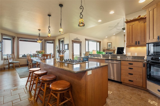 kitchen featuring a center island, pendant lighting, black appliances, a kitchen bar, and ceiling fan