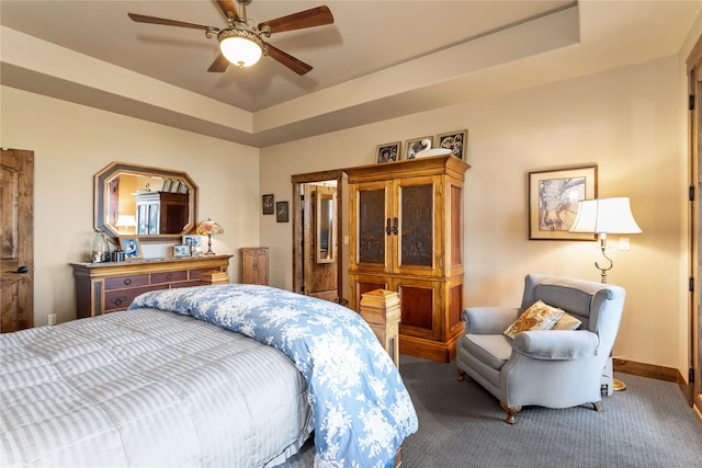 bedroom featuring ceiling fan, baseboards, carpet flooring, and a tray ceiling