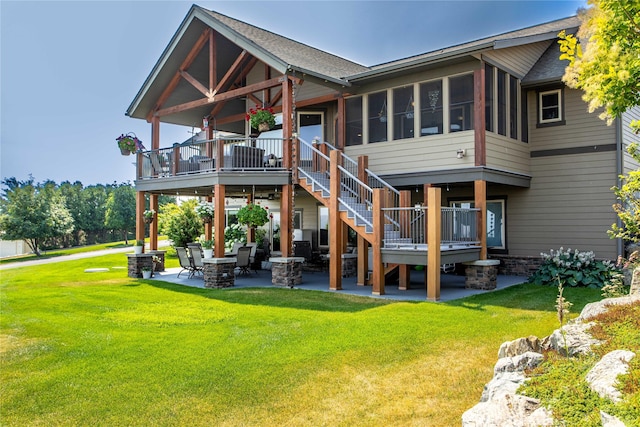 rear view of property featuring a patio area, a lawn, and roof with shingles