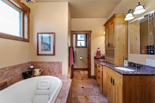 bathroom with a relaxing tiled tub, tile patterned floors, and vanity