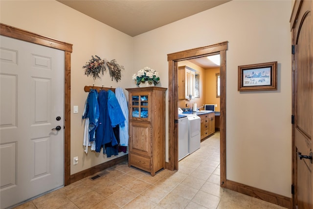 foyer featuring visible vents, washing machine and clothes dryer, baseboards, and light tile patterned floors