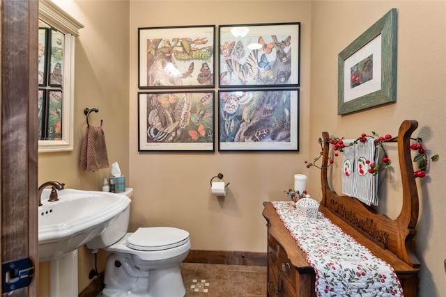 half bathroom with baseboards, toilet, and tile patterned floors