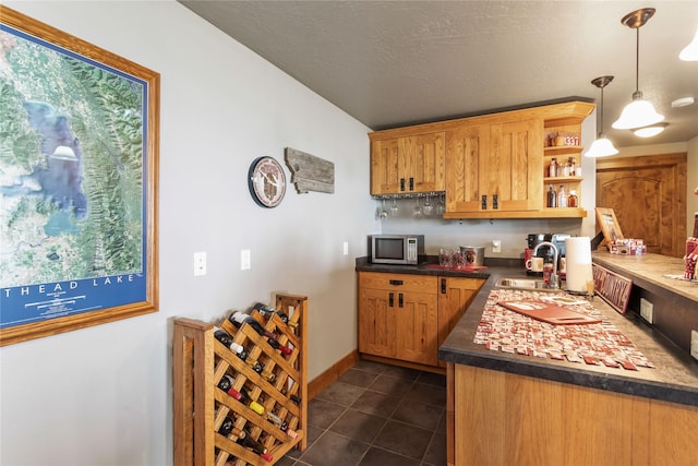 kitchen with open shelves, dark countertops, a sink, stainless steel microwave, and dark tile patterned floors