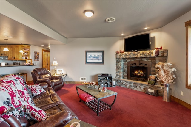carpeted living room with baseboards, a stone fireplace, visible vents, and recessed lighting