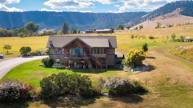 rear view of house with stairway, a deck with mountain view, and a yard