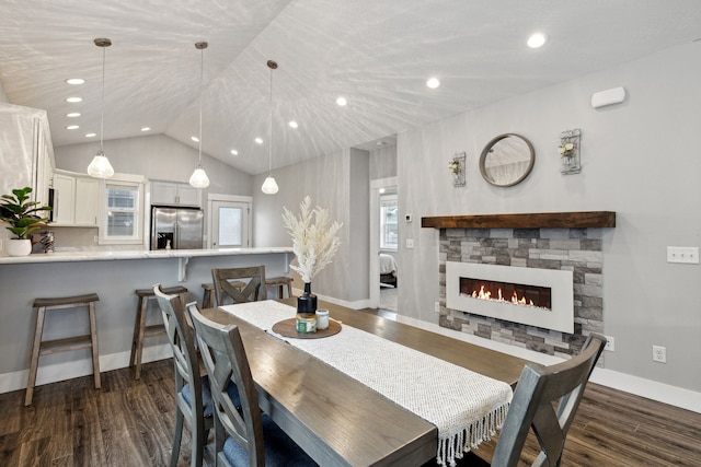 dining room with a fireplace, dark wood-type flooring, and vaulted ceiling