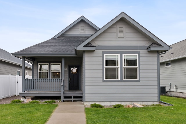 bungalow-style house featuring a porch, cooling unit, and a front lawn