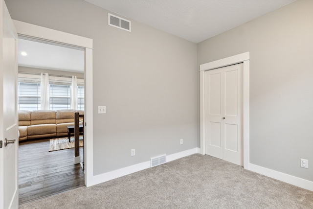 carpeted empty room with visible vents and baseboards