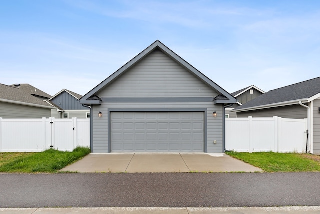 view of front of home with an outbuilding, a detached garage, fence, and a gate