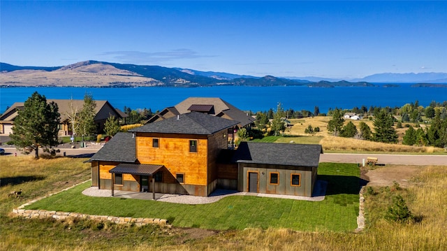 rear view of house with a water and mountain view and a yard