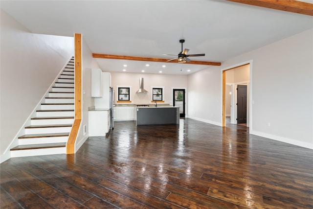 unfurnished living room featuring ceiling fan, beamed ceiling, and dark hardwood / wood-style floors