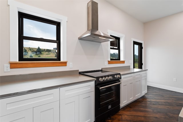 kitchen with a healthy amount of sunlight, white cabinets, electric range, and wall chimney range hood