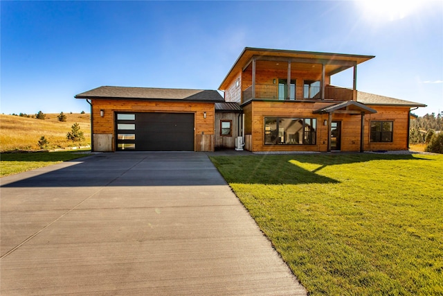 view of front of property with a garage, a balcony, and a front lawn