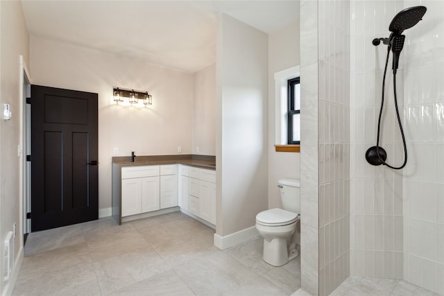 bathroom featuring a tile shower, vanity, and toilet