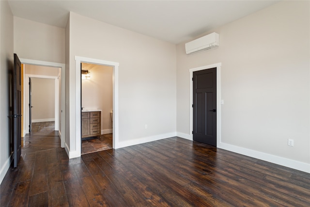 unfurnished bedroom featuring a wall mounted air conditioner, dark hardwood / wood-style floors, and ensuite bathroom