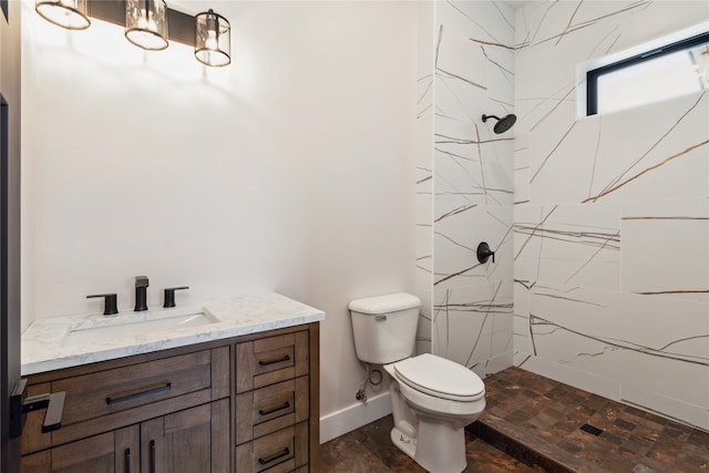 bathroom with a tile shower, vanity, and toilet