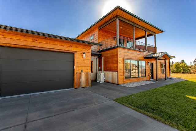 contemporary house with a balcony, ac unit, a garage, and a front yard