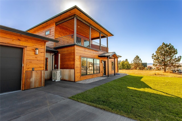 exterior space featuring a garage, a balcony, ac unit, and a yard