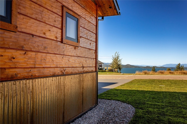 view of side of home with a mountain view and a yard