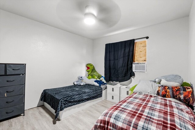 bedroom featuring light hardwood / wood-style flooring, ceiling fan, and cooling unit