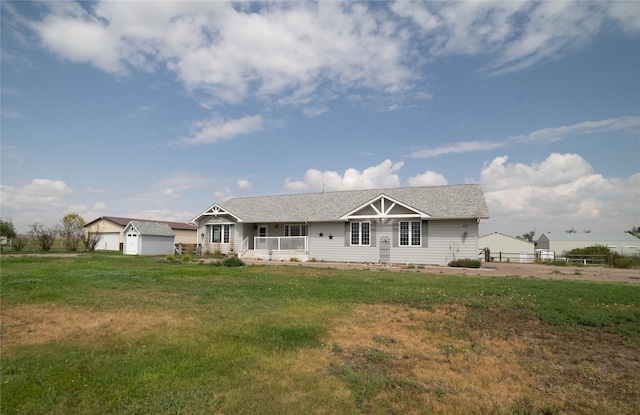 view of front of property featuring a garage, a front yard, fence, and an outbuilding