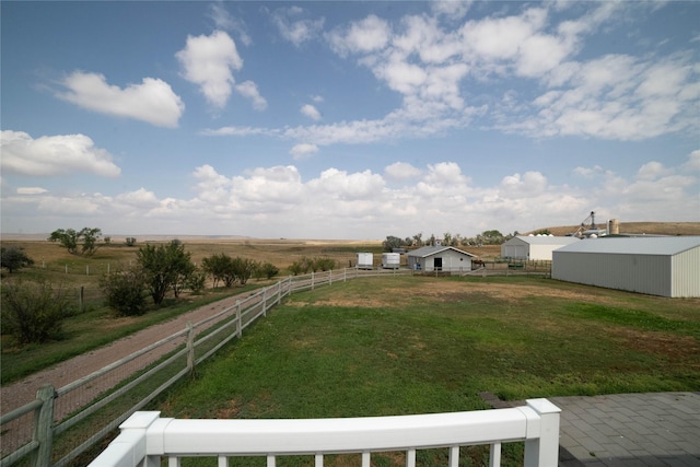 view of yard with fence, an outbuilding, and a rural view