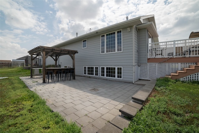 back of property featuring fence, outdoor dry bar, a wooden deck, a pergola, and a patio area