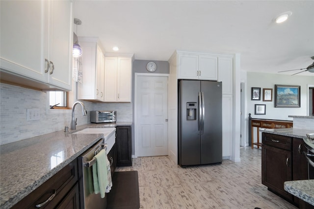 kitchen featuring appliances with stainless steel finishes, white cabinets, and light stone counters