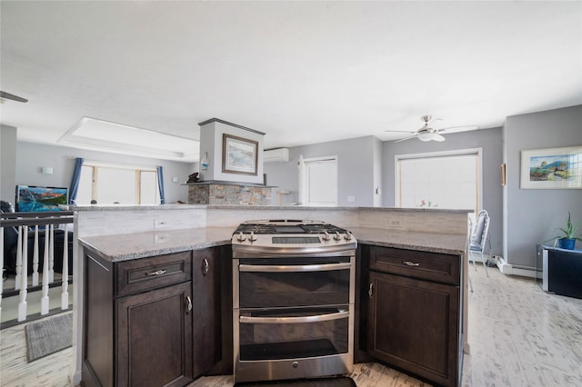 kitchen with dark brown cabinetry, light wood finished floors, range with two ovens, a peninsula, and light stone countertops