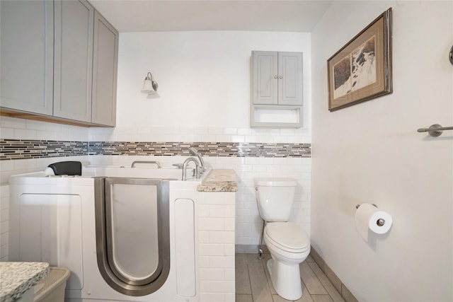 bathroom with tile walls and toilet