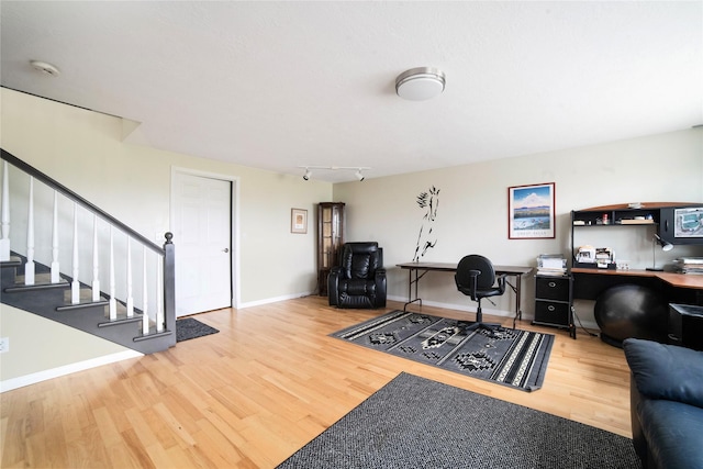 home office featuring track lighting, wood finished floors, and baseboards