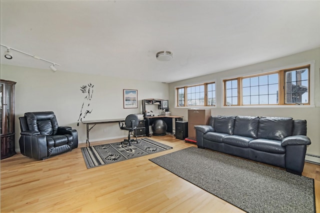 living room with a baseboard heating unit, wood finished floors, rail lighting, and baseboards