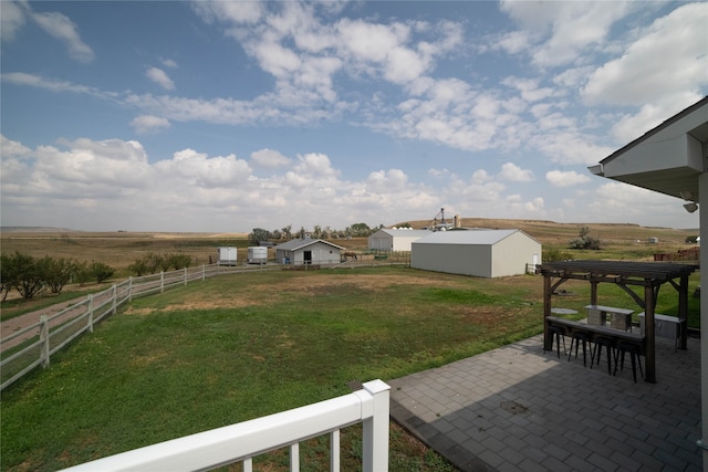 view of yard featuring a rural view, a patio area, fence, and a pergola