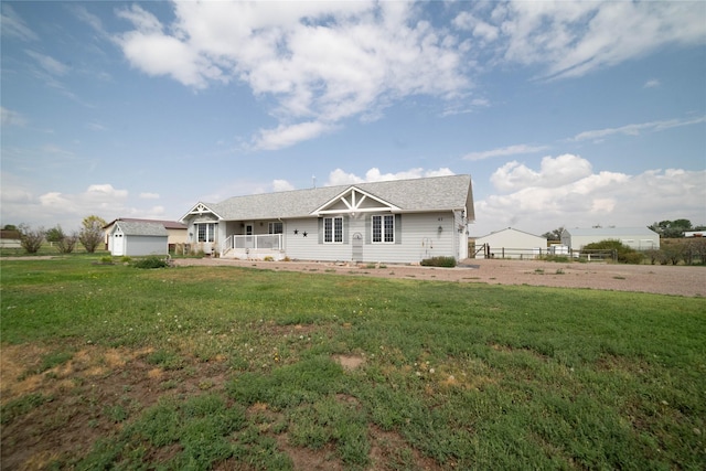 view of front of property with fence, a storage unit, a front lawn, and an outdoor structure