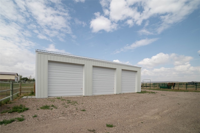 detached garage with fence and a rural view